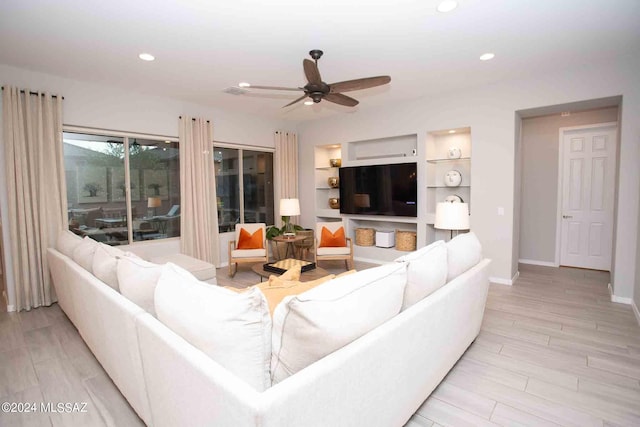 living room featuring ceiling fan, light hardwood / wood-style flooring, and built in shelves