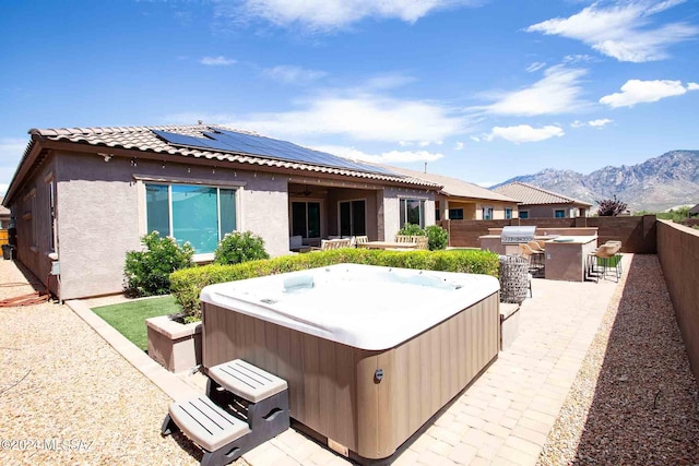 rear view of property featuring a fenced backyard, outdoor dry bar, a mountain view, a hot tub, and stucco siding