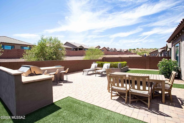 view of patio with an outdoor kitchen, a fenced backyard, outdoor dining area, and a residential view