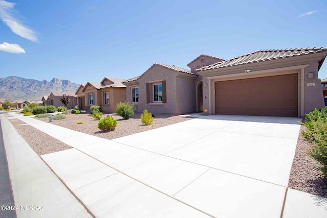 view of front of house featuring stucco siding, a mountain view, concrete driveway, and a garage
