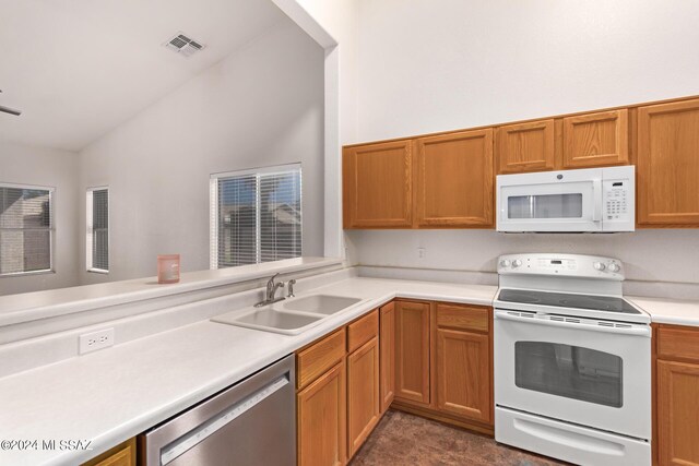 kitchen with dark tile patterned flooring, sink, lofted ceiling, kitchen peninsula, and white appliances