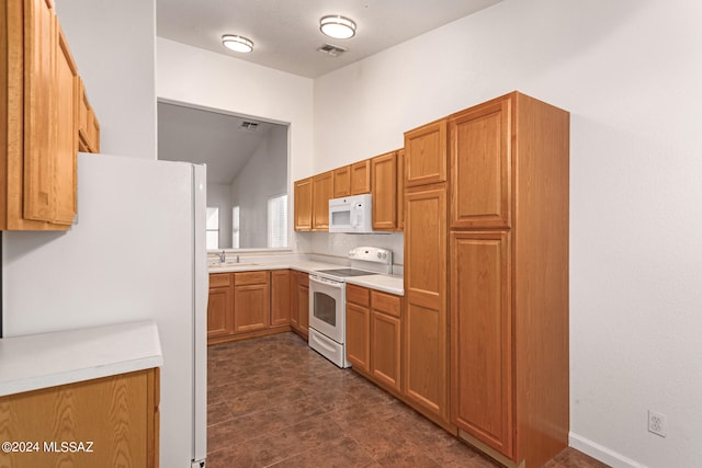 kitchen with white appliances, vaulted ceiling, sink, and dark tile patterned floors