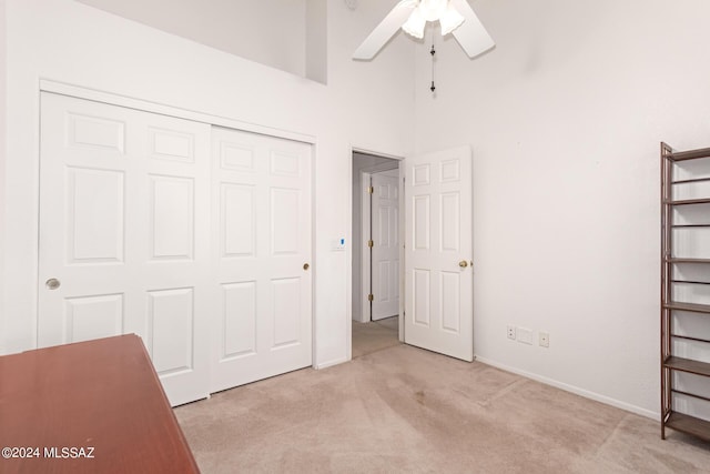 unfurnished bedroom with a closet, baseboards, a towering ceiling, ceiling fan, and carpet floors