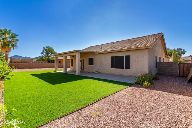 back of property featuring a mountain view, a patio area, and a yard