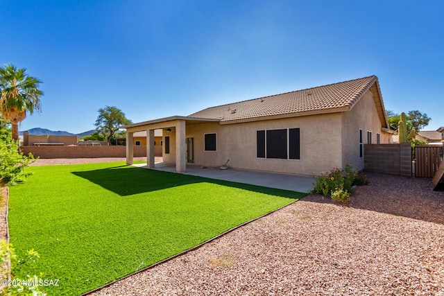 rear view of house with a tile roof, stucco siding, fence, a patio area, and a lawn