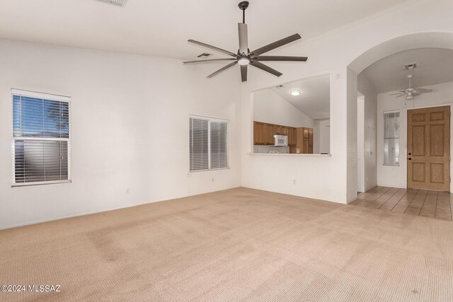 unfurnished living room with ceiling fan, light carpet, and vaulted ceiling