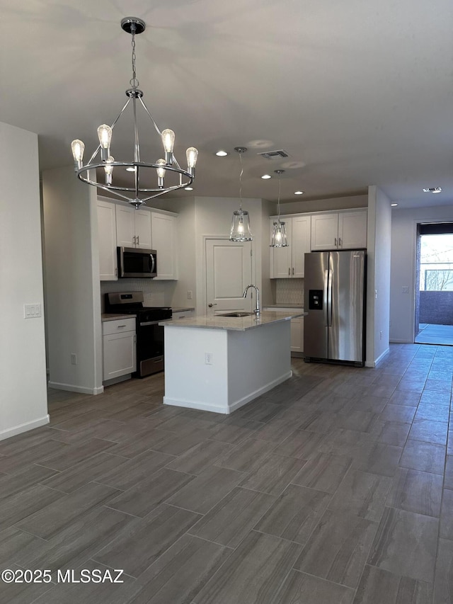 kitchen featuring pendant lighting, a center island with sink, white cabinets, and appliances with stainless steel finishes