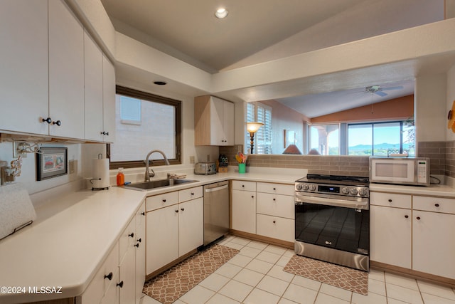 kitchen with decorative backsplash, white cabinetry, stainless steel appliances, lofted ceiling, and sink