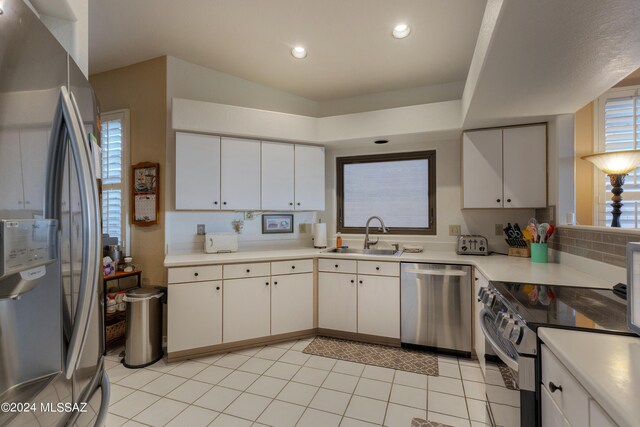 kitchen featuring white cabinets, appliances with stainless steel finishes, light tile patterned floors, and sink