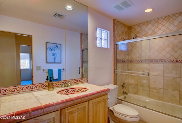 full bathroom featuring a healthy amount of sunlight, visible vents, toilet, and combined bath / shower with glass door