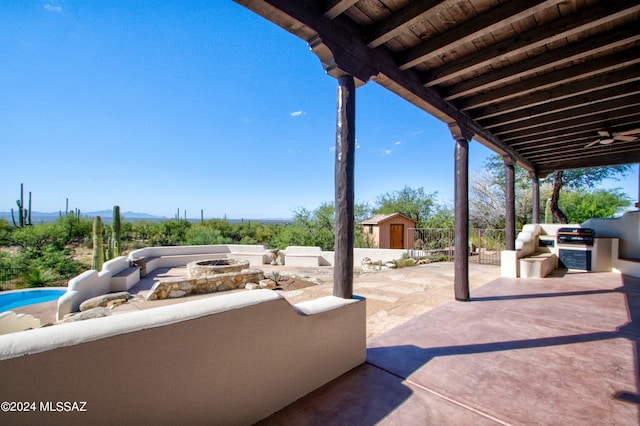 view of patio with exterior kitchen, an outdoor fire pit, an outdoor structure, and fence