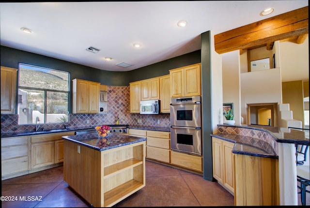 kitchen featuring dark tile patterned flooring, a center island, a kitchen breakfast bar, stainless steel appliances, and light brown cabinets