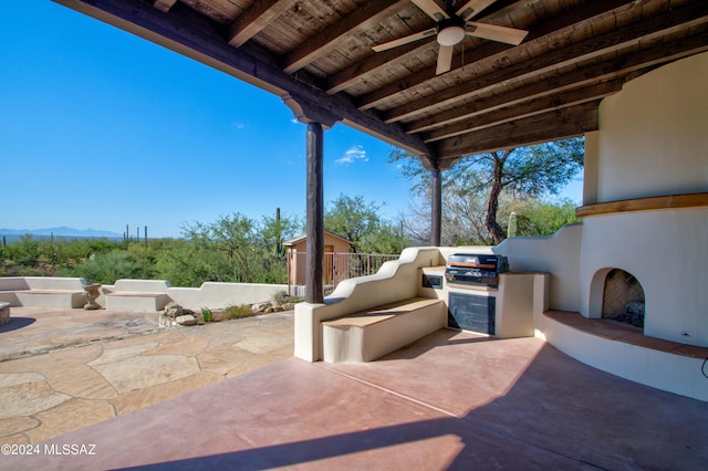 view of patio with a large fireplace, an outdoor kitchen, ceiling fan, an outdoor structure, and a mountain view