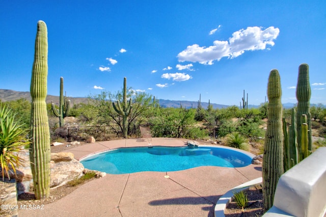 view of swimming pool featuring a fenced in pool, a mountain view, and a patio