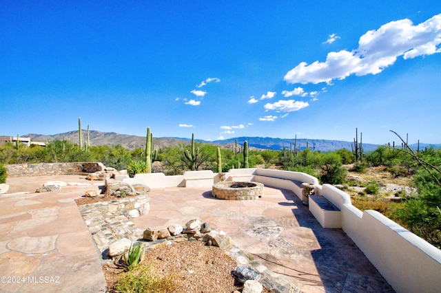 view of patio with an outdoor fire pit and a mountain view