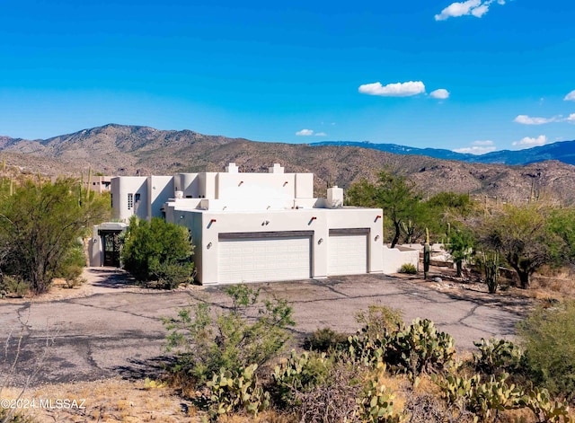 view of front of home with an attached garage, a mountain view, driveway, stucco siding, and a chimney