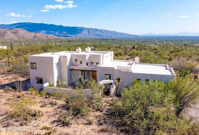 view of front facade featuring a chimney, a mountain view, and stucco siding