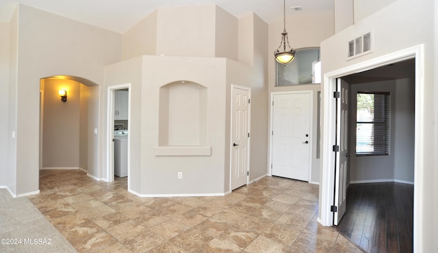 foyer with a high ceiling, washer / dryer, and light hardwood / wood-style flooring