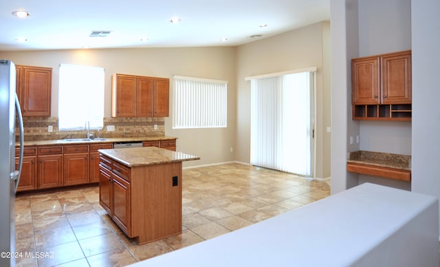 kitchen featuring lofted ceiling, a center island, stainless steel appliances, tasteful backsplash, and sink