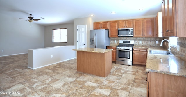 kitchen featuring light stone counters, a center island, stainless steel appliances, tasteful backsplash, and sink