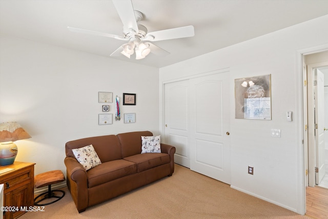 living room featuring ceiling fan, light colored carpet, and baseboards