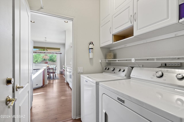 laundry area featuring cabinet space, washer and clothes dryer, and wood finished floors