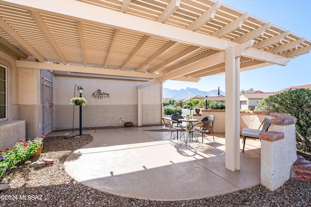 view of patio with outdoor dining space, a pergola, and a mountain view