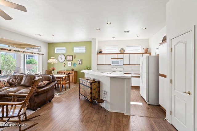 kitchen with white appliances, light hardwood / wood-style flooring, decorative light fixtures, white cabinetry, and a center island