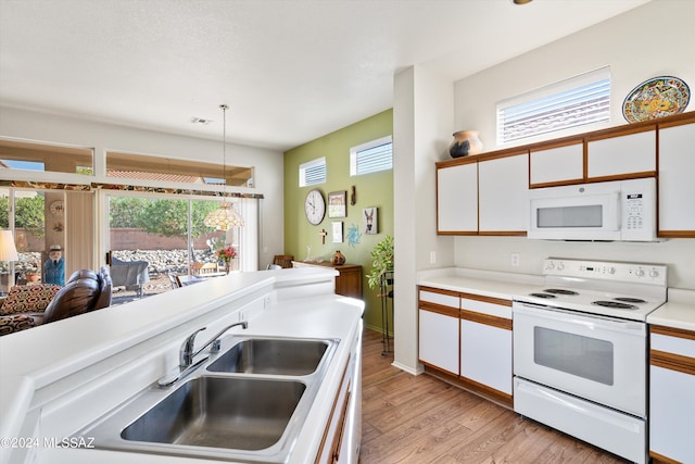 kitchen with hanging light fixtures, sink, white appliances, light hardwood / wood-style flooring, and white cabinetry