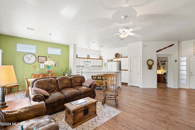living area with light wood finished floors, ceiling fan, and visible vents