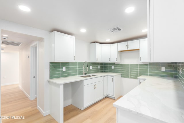 kitchen with light hardwood / wood-style flooring, white cabinets, light stone counters, and sink