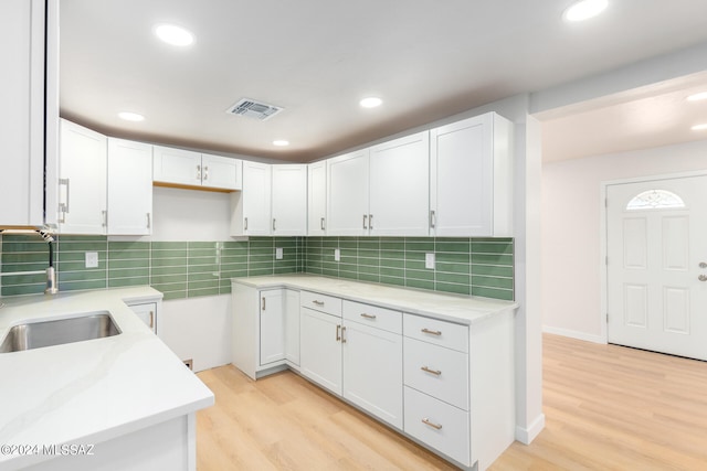 kitchen featuring light wood-type flooring, white cabinetry, sink, and tasteful backsplash