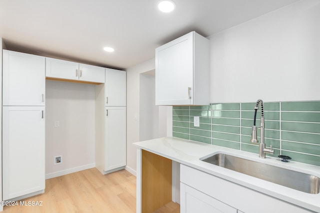 kitchen featuring white cabinets, light wood-type flooring, and sink