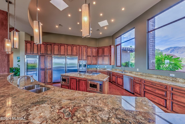 kitchen with built in appliances, a mountain view, a skylight, and sink