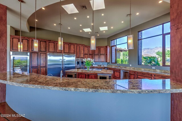 kitchen featuring visible vents, a sink, stone countertops, and built in appliances