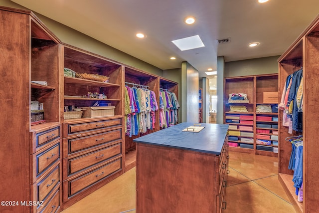 walk in closet with a skylight and light tile patterned floors