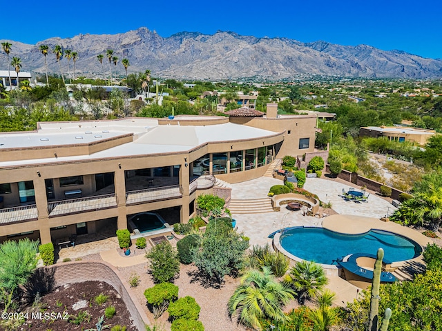 view of swimming pool with a patio, a mountain view, and an in ground hot tub