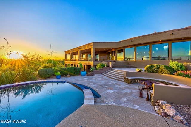 pool at dusk featuring a patio