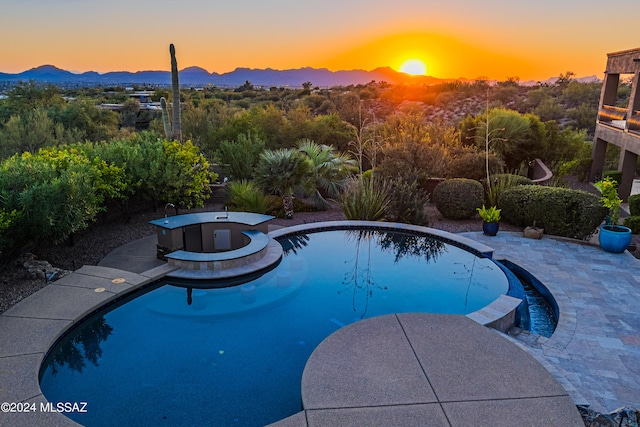 pool at dusk with a mountain view and a patio area