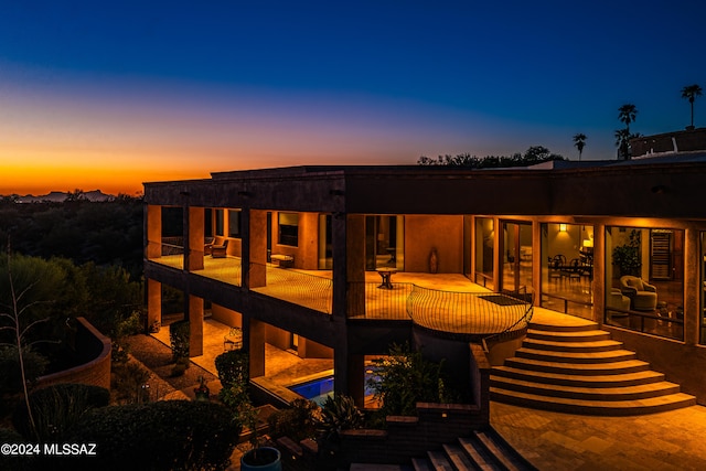 back house at dusk featuring a patio area