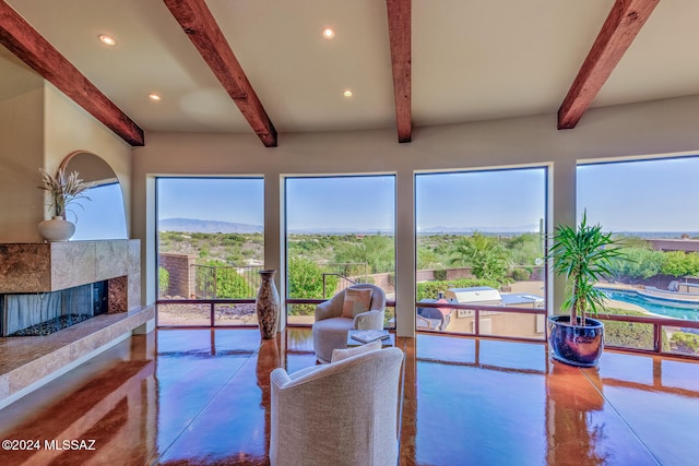 living room featuring beam ceiling, concrete flooring, a fireplace, and a mountain view