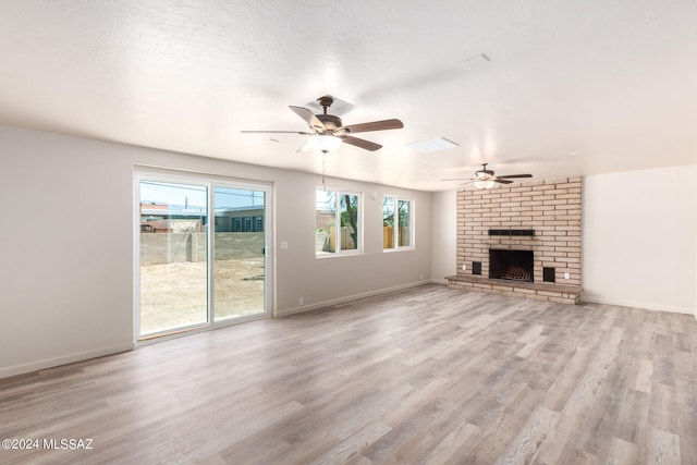 unfurnished living room with a textured ceiling, light hardwood / wood-style floors, ceiling fan, and a brick fireplace