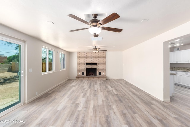 unfurnished living room featuring ceiling fan, a fireplace, and light hardwood / wood-style floors