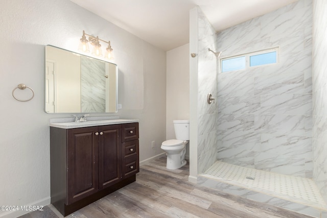 bathroom with tiled shower, hardwood / wood-style flooring, vanity, and toilet