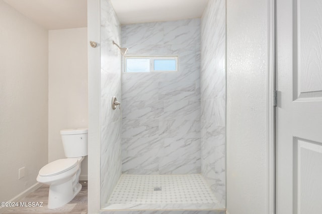 bathroom featuring hardwood / wood-style floors, toilet, and tiled shower