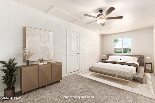 carpeted bedroom with ceiling fan, a textured ceiling, and brick wall