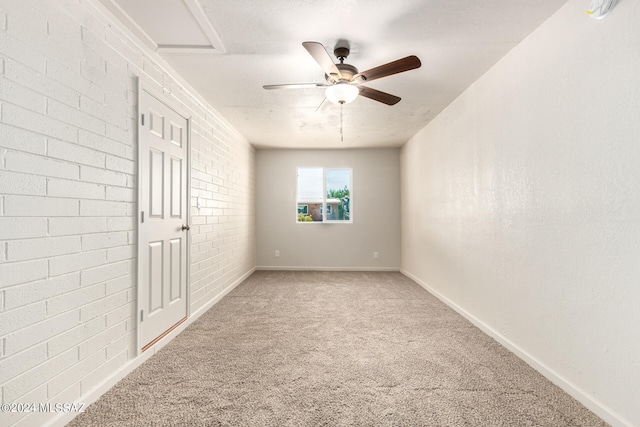 unfurnished bedroom with light carpet, ceiling fan, brick wall, and a textured ceiling