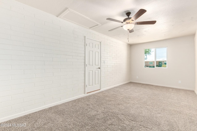 unfurnished bedroom with a textured ceiling, carpet flooring, ceiling fan, and brick wall