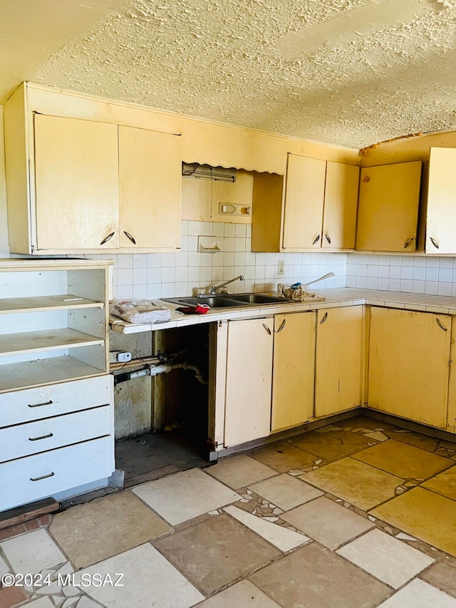 kitchen with backsplash, a textured ceiling, and light brown cabinets