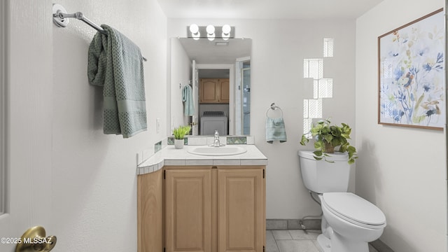 bathroom with toilet, washer / dryer, vanity, and tile patterned floors